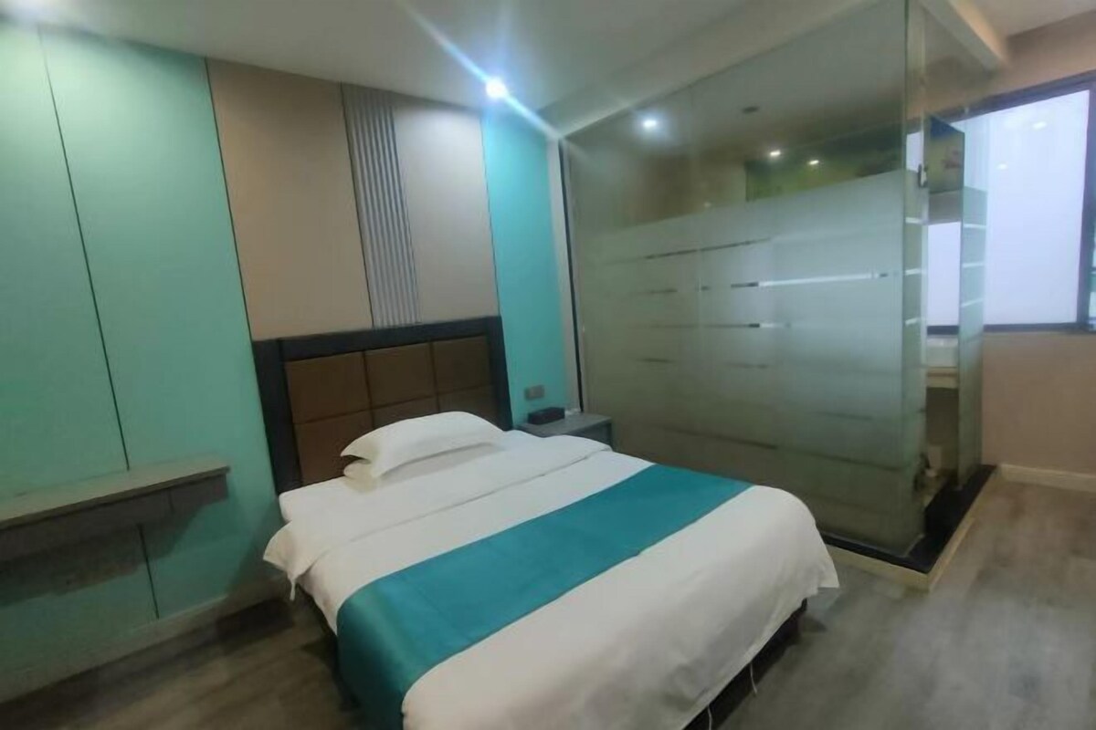 Hotelkamer met een bed, nachtkastje, bankje en een schuifdeur naar een badkamer.