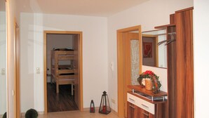 Ein Zimmer mit einem Holzschrank, einem kleinen Holztisch, einem roten Teppich und einer Tür zu einem anderen Raum.