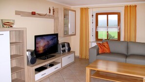 Una sala de estar con televisor, parlantes, un sofá y una mesa de centro.