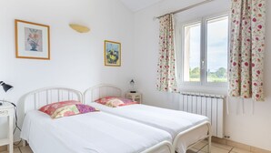 Ein Schlafzimmer mit zwei Betten, einem Fenster mit blumigen Vorhängen und einer Heizung.