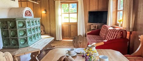 A wooden interior with a dining table set for breakfast, a red sofa, and a television mounted on the wall.