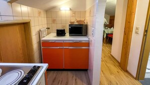 Uma cozinha compacta com micro-ondas, torradeira e uma cesta sobre o balcão.