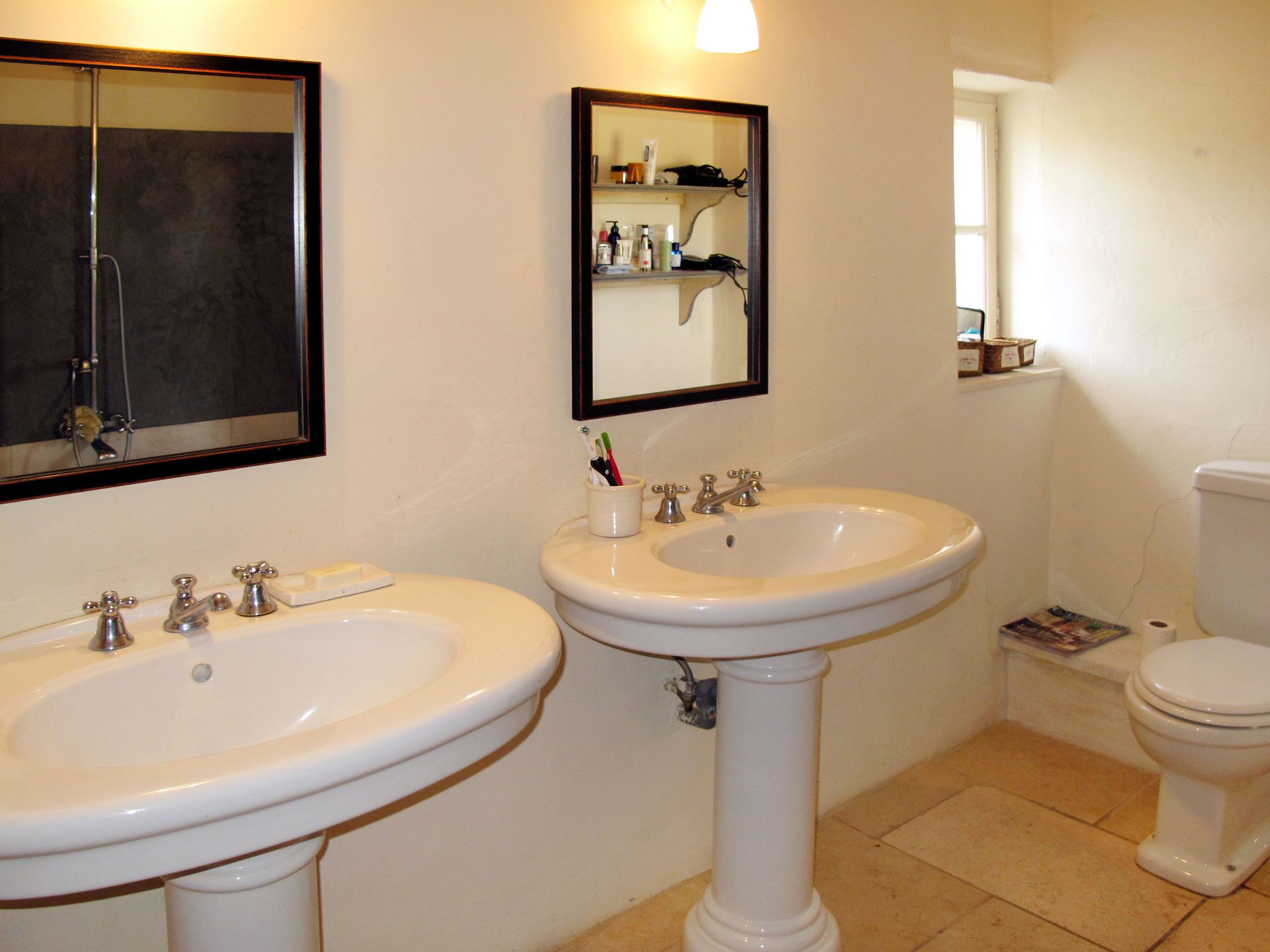 A bathroom with two sinks, a toilet, and a mirror.