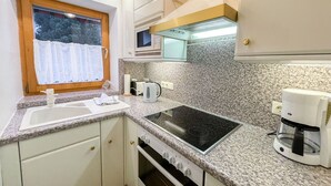 Una cocina compacta con encimera de granito, microondas integrado, estufa y cafetera.