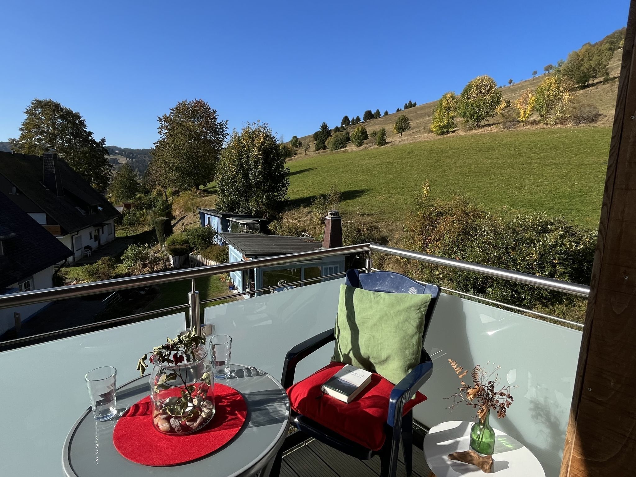 Een balkon met een tafel gedekt voor twee, met uitzicht op een landelijk landschap met huizen en bomen.