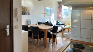 A modern kitchen with a stove, a dining area with a table and chairs, and a living area with a sofa. - Schwarzwaldblick III by Interhome (Bernau)