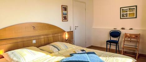 Une chambre à coucher avec un lit, une chaise, un bureau et une porte.