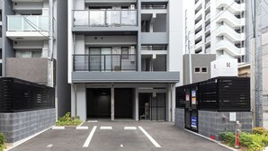 Ein modernes Gebäude mit geschlossenem Eingangsbereich, mehreren Etagen und einer Schilder mit der Aufschrift 'Wohnhotel'.