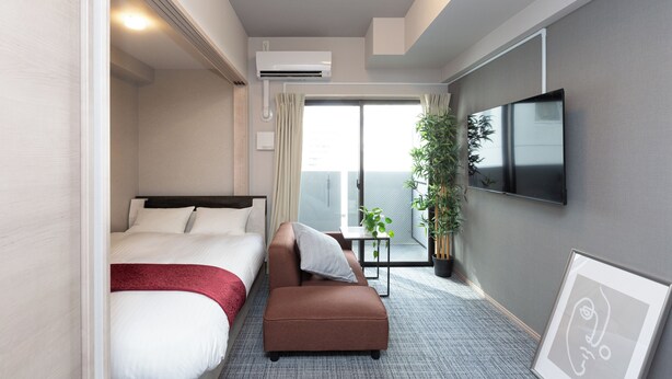 Ein Hotelzimmer mit Bett, einer Sitzecke, einem Fernseher, einer Pflanze und einem Balkon mit Aussicht.