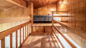 Una baita in legno con un letto a castello, ringhiere di legno e un tetto spiovente.