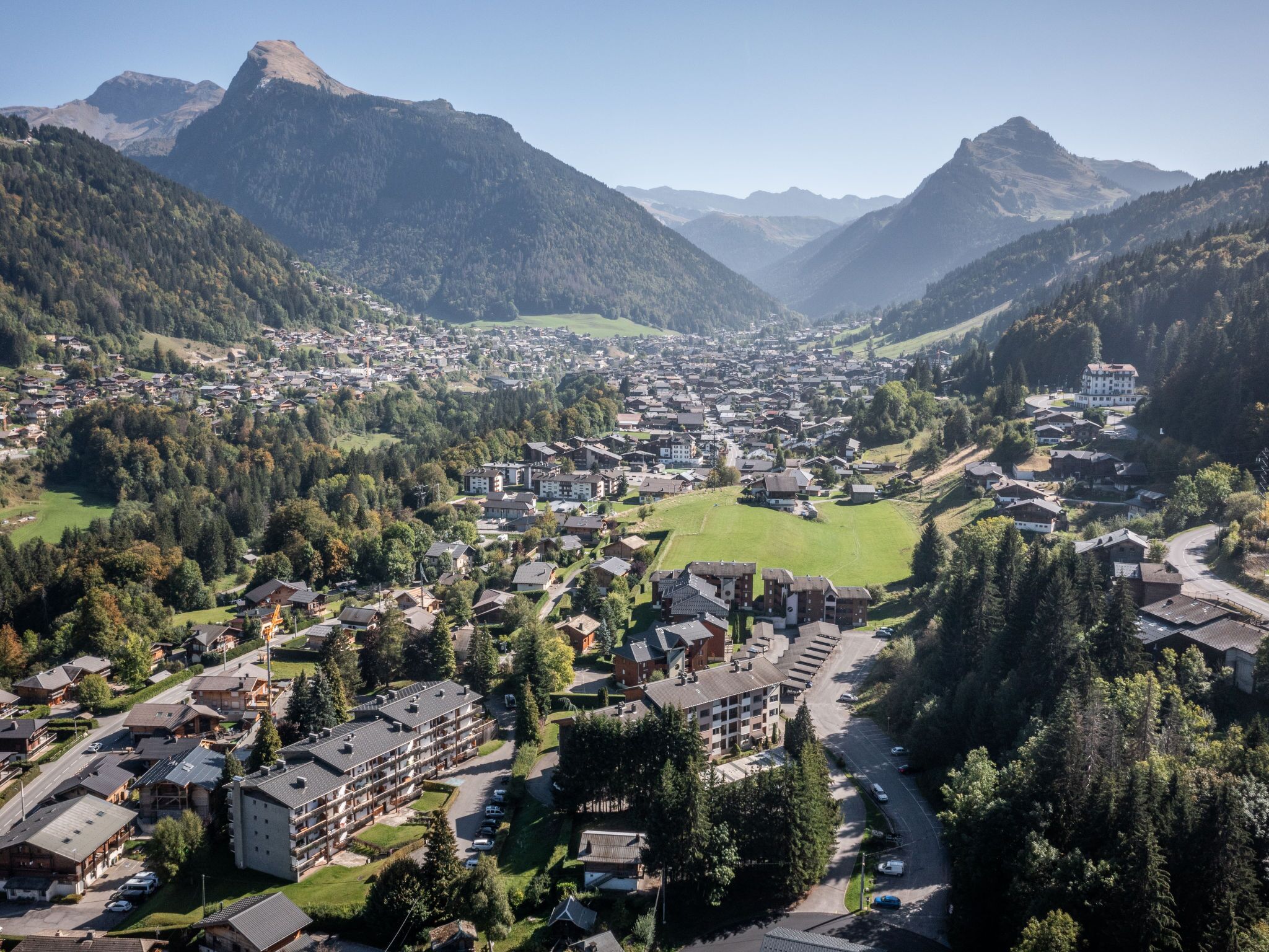 A town nestled in a valley with a mix of residential and commercial buildings, surrounded by mountains.