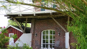 Ein Backsteinhaus mit überdachter Terrasse, einer weißen Tür und einem Fenster.