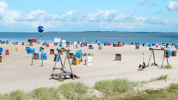 Ein Strand mit vielen farbenfrohen Behältern und einem großen blauen Ballon.
