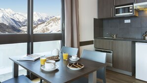 Eine moderne Küche mit Blick auf schneebedeckte Berge, einem Esstisch mit Frühstücksangeboten und einer eingebauten Mikrowelle.