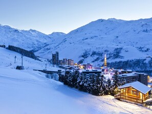 A snow-covered mountain town with a prominent church tower, ski slopes, and modern buildings.