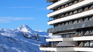 Ein modernes Gebäude mit mehreren Balkonen mit Blick auf einen verschneiten Berg.