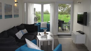 A modern living room with a sofa, a coffee table, and a TV mounted on the wall. - Tossens by Interhome (Tossens)