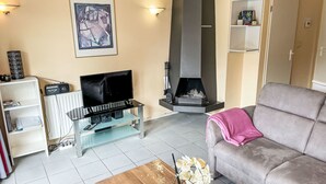 A living room with a fireplace, a sofa, a coffee table, and a TV on a stand. - Tossens by Interhome (Tossens)