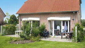 A two-story house with a red-tiled roof, a brick exterior, and a small patio with outdoor furniture. - Tossens by Interhome (Tossens)