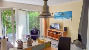 A modern living room with a TV, wooden entertainment unit, and a painting on the wall. - Tossens by Interhome (Tossens)