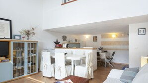 A modern living room with a dining area, a kitchen, and a sofa.