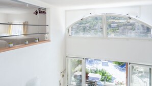 A modern room with a bed, a small table, and a window overlooking a garden.
