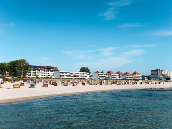 A beachside hotel with multiple buildings, a sandy beach, and a calm sea.