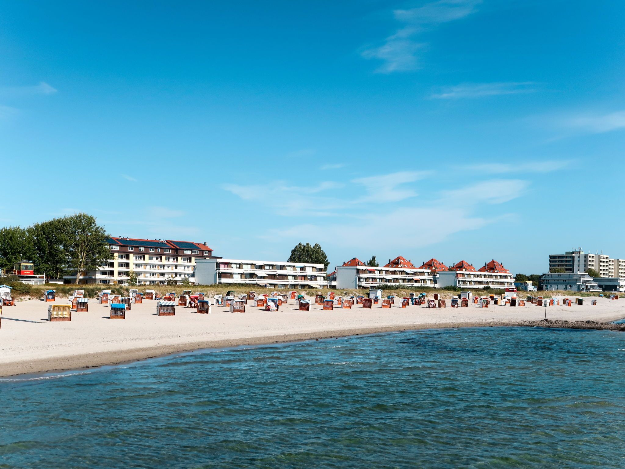 A beachside hotel with multiple buildings, a sandy beach, and a calm sea.