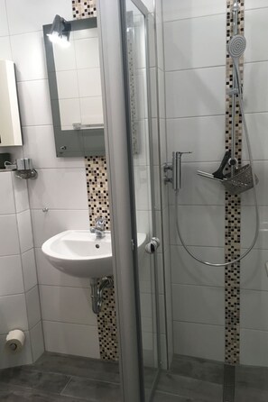 A modern bathroom with a glass-enclosed shower, a white sink, and a tiled backsplash. - Ostsee-Residenz (DMP153) by Interhome (Damp)
