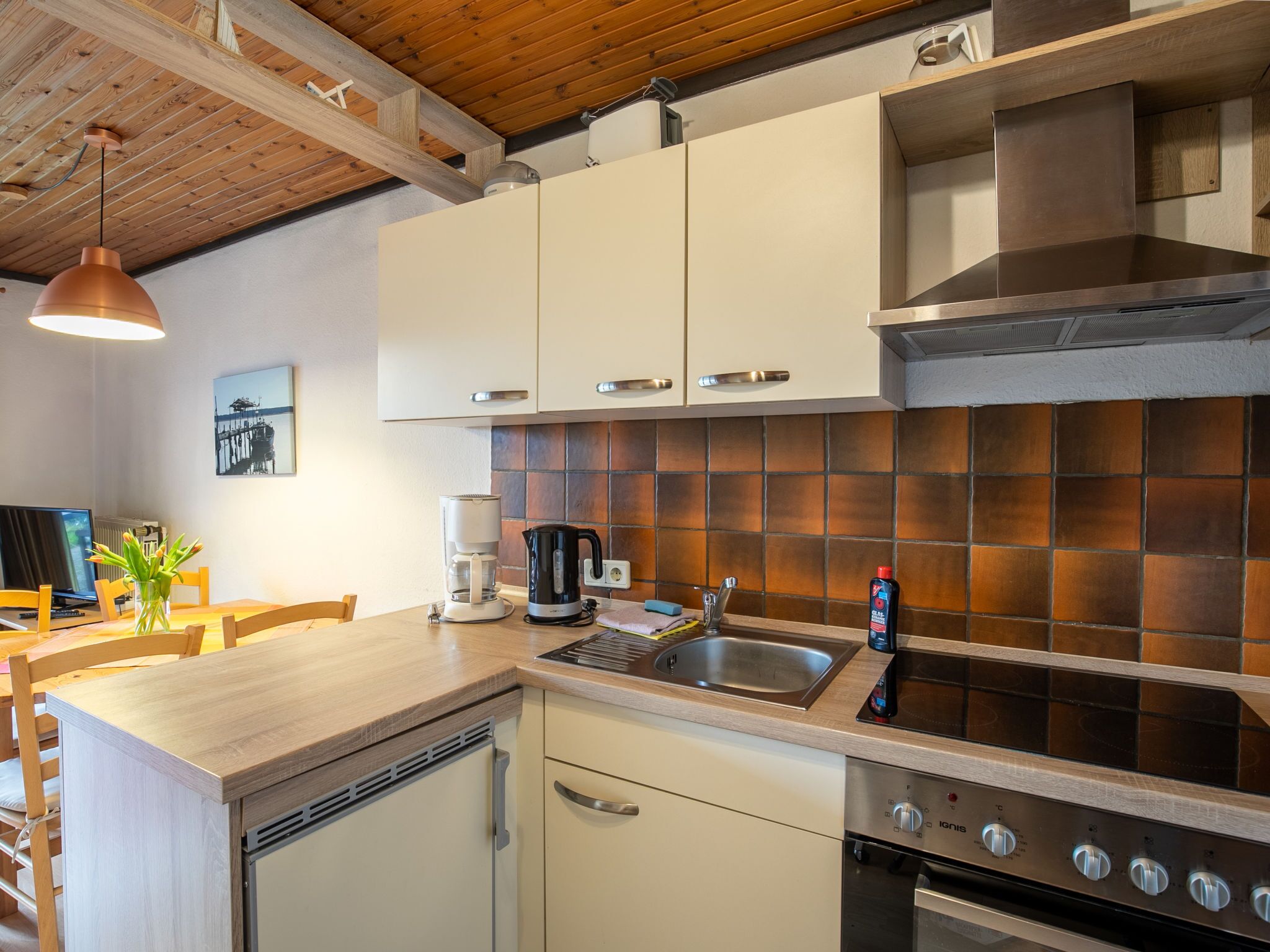 Una cocina moderna con armarios blancos, un lavamanos de acero inoxidable y un horno empotrado.