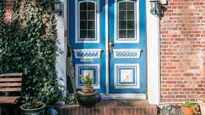 A blue door with white trim, a green roof, and a brick wall.