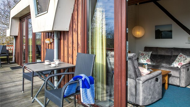 A modern outdoor seating area with a table and chairs, a sofa, and a wooden deck.