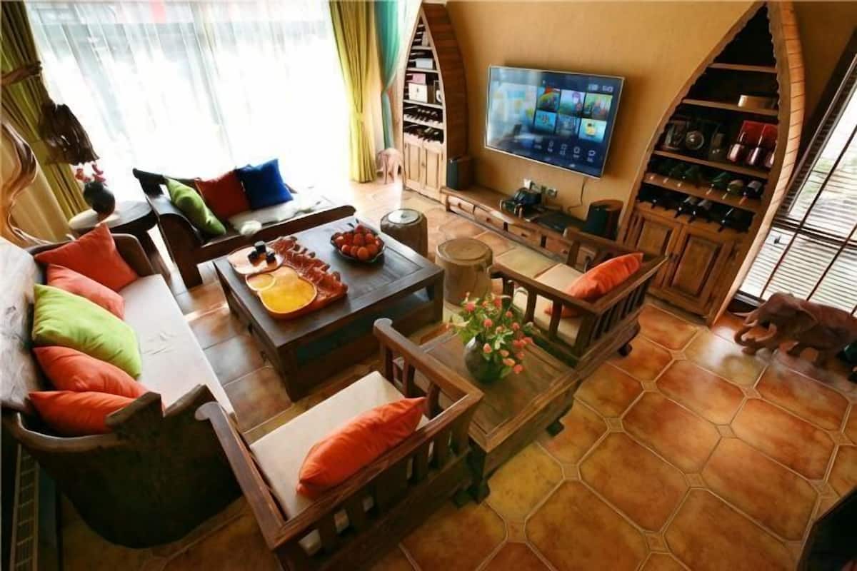 A living room with a sofa, coffee table, and TV. There are bookshelves and a dog in the room.