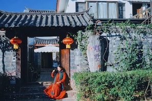 Un bâtiment traditionnel chinois, avec un toit recouvert de tuiles, des colonnes en bois et un mur en pierre.