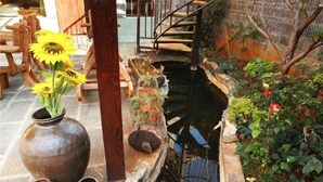 A rustic outdoor area with a small pond, wooden furniture, and large vases. - Dieshu Private Holiday Villa (Lijiang)
