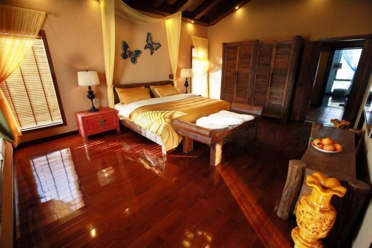 A bedroom with a wooden bed, a nightstand, a dresser, and a wooden chair.