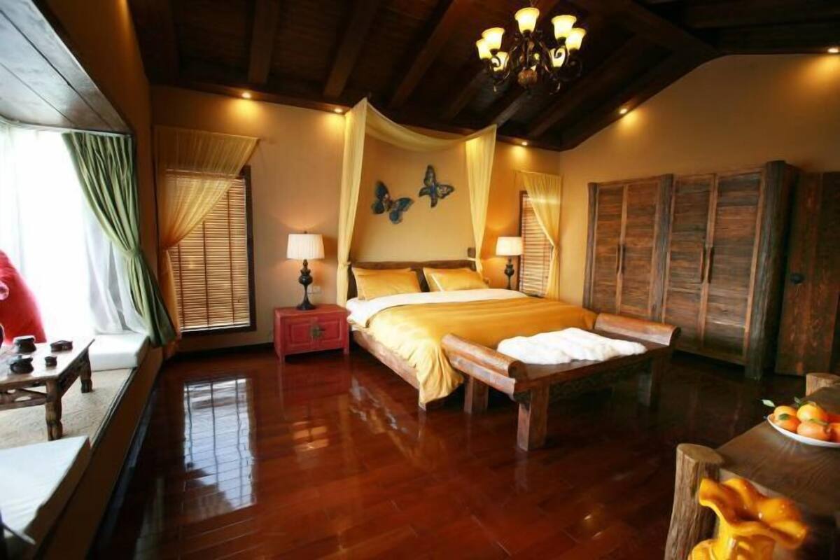 A spacious bedroom with a large bed, wooden furniture, and a chandelier.