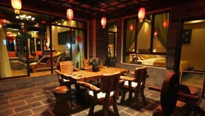 A traditional wooden dining table with chairs, surrounded by brick flooring and red lanterns. - Dieshu Private Holiday Villa (Lijiang)