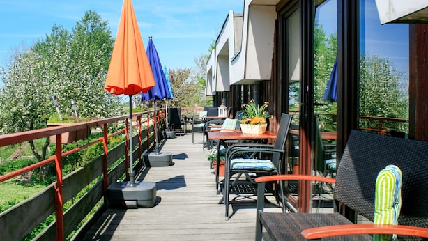 Eine Holzterrasse mit Außenmöbeln, Sonnenschirmen und einem Geländer.