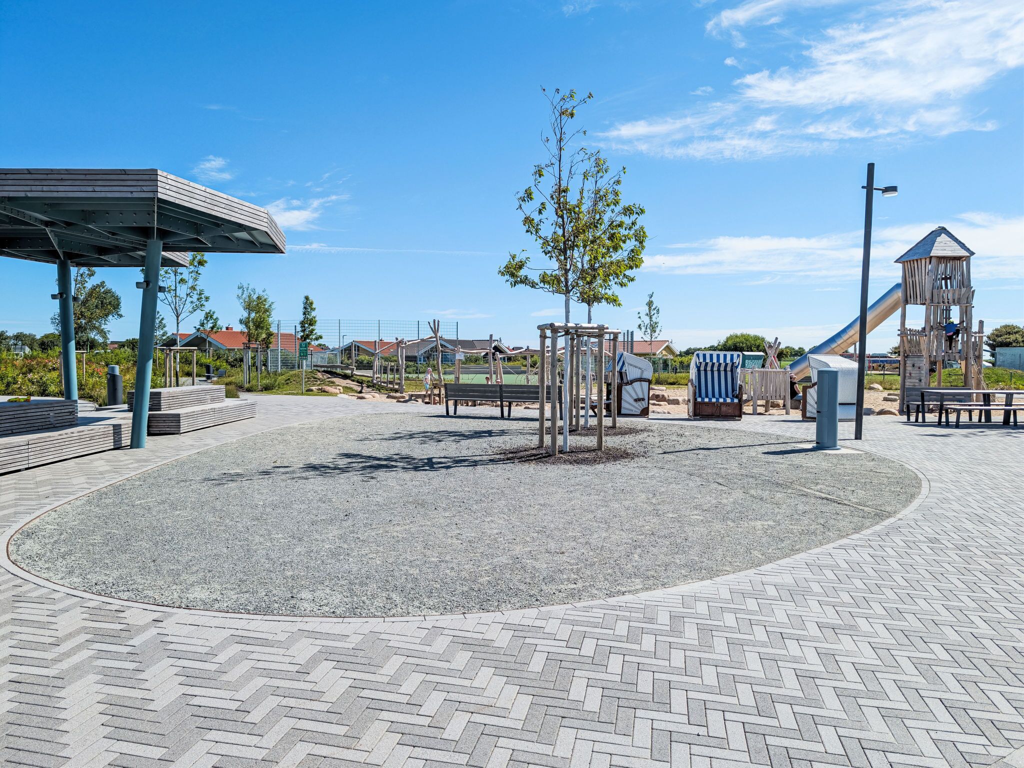 A playground with a covered seating area, a climbing structure, and a slide.