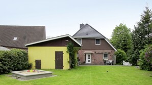 A two-story house with a sloped roof, a small attached garage, and a well-maintained lawn.