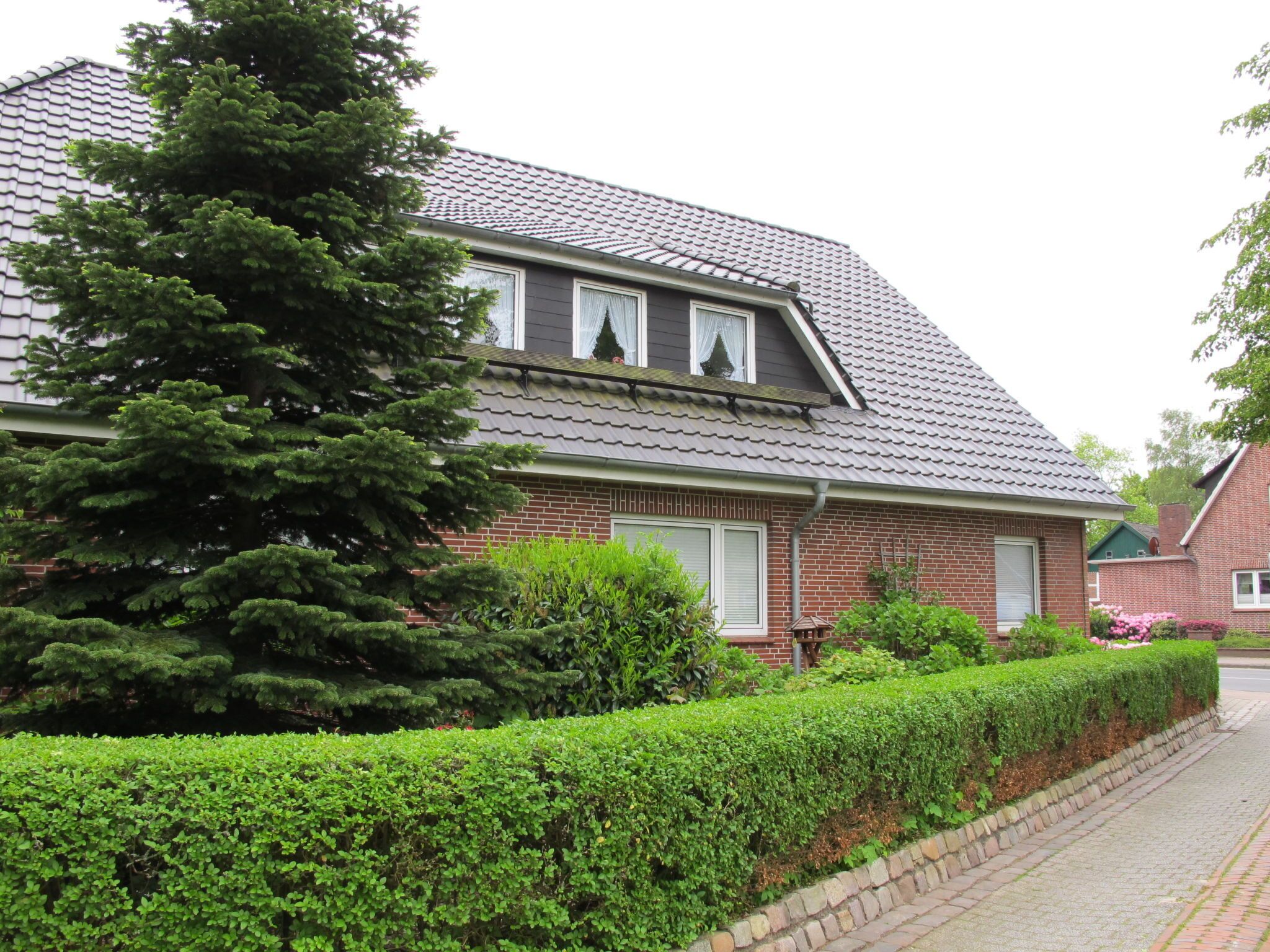 Ein zweistöckiges Haus mit Ziegelverkleidung, Dachgauben und einem geneigten Dach.