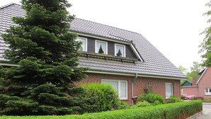A two-story house with a brick facade, dormer windows, and a sloped roof.