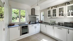 Eine moderne Küche mit weißen Schränken, einem eingebauten Backofen und einem großen Fenster.