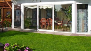 A modern house with a glass door leading to a patio area with wicker furniture. - Osterende by Interhome (Otterndorf)