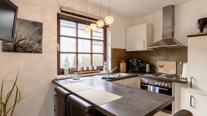 Una cocina moderna con una isla central, electrodomésticos de acero inoxidable e iluminación colgante.