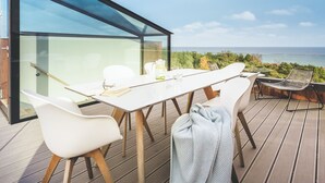A modern outdoor dining area with a glass wall overlooking the sea. - Mariandl am Meer by Interhome (Ostseebad Binz)
