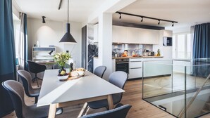A modern kitchen with a central island, a dining area with a white table and chairs, and a glass partition separating the two spaces. - Mariandl am Meer by Interhome (Ostseebad Binz)