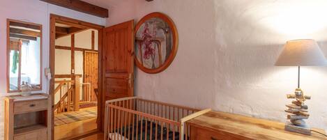 A cozy room with a wooden crib, a dresser, a mirror, and a lamp.