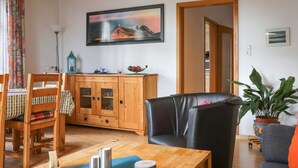 Ein gemütliches Wohnzimmer mit Holzmöbeln, einem großen Gemälde und einem Blumentopf.